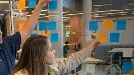 Students place sticky notes on a wall during an exercise in health innovation 和 entrepreneurship